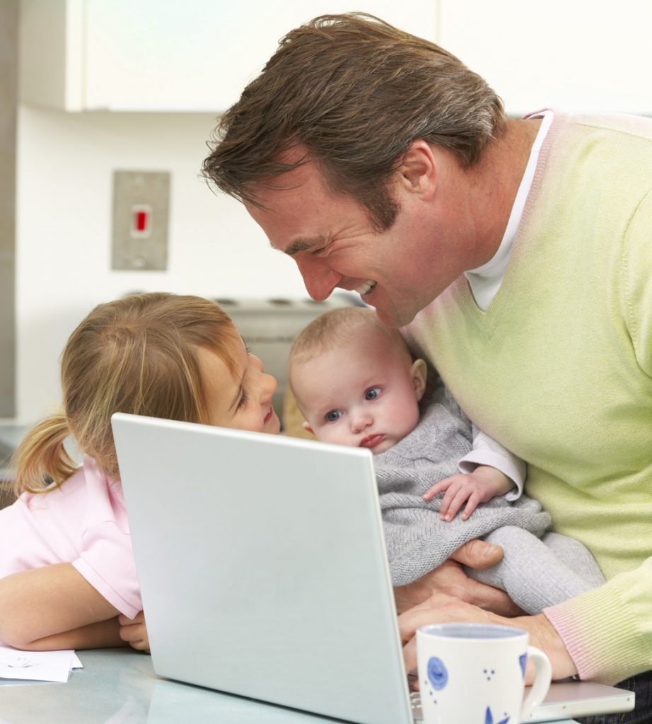 Father with children using laptop in kitchen